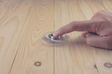 Tahta masanın üzerinde dönen oyuncakla (kıpırdanma) elin klasik ton görüntüsü.