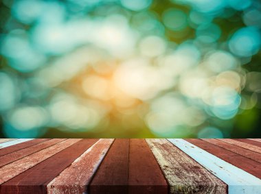 Arkaplan kullanımı için ahşap tablo ve yeşil ağaç bokeh 'in soyut bulanık resmi .