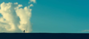 Arkaplanda gündüz vakti bulanık mavi gökyüzü olan fotoğrafçının minyatür bebek fikri..