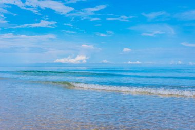 Arka planda mavi gökyüzü olan deniz kıyısındaki dalgaların görüntüsü.