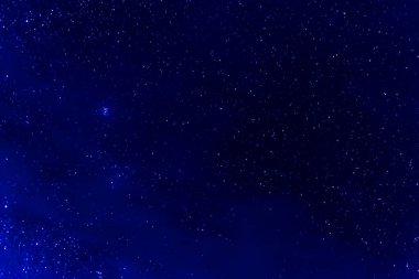 Güzel mavi gökyüzünün ve arkaplandaki yıldızların uzun pozlama görüntüsü.