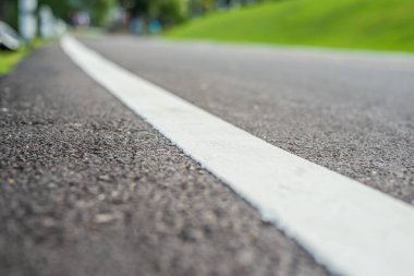 Mavi yeşil bahçeyi görmek için gündüz vakti asfalt yolu görüntüsü. (sokak dokusuna odaklan)