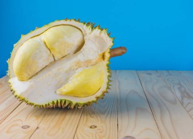 Ahşap masa üzerinde sarı posası olan olgun durian resmi.