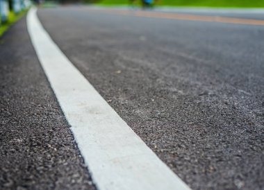 Mavi yeşil bahçeyi görmek için gündüz vakti asfalt yolu görüntüsü. (sokak dokusuna odaklan)