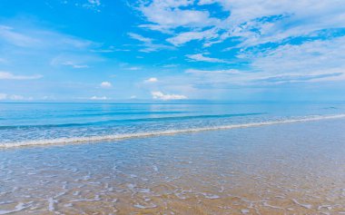 Arka planda mavi gökyüzü olan deniz kıyısındaki dalgaların görüntüsü.