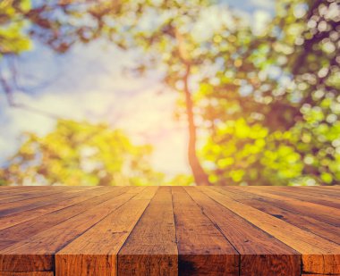 Arkaplan kullanımı için ahşap tablo ve yeşil ağaç bokeh 'in soyut bulanık resmi .