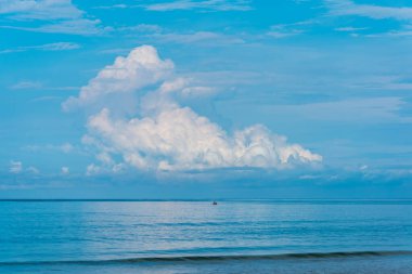 Denizde kayık resmi ve bulutlu mavi gökyüzü..