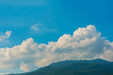 Tropikal yeşil dağ ormanının ve bulutlu gökyüzünün gündüz görüntüsü.
