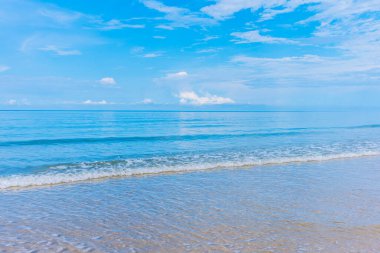 Arka planda mavi gökyüzü olan deniz kıyısındaki dalgaların görüntüsü.