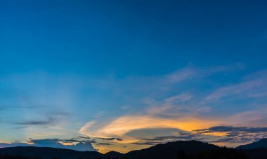 Arkaplanda dağ ve günbatımı görüntüsü.