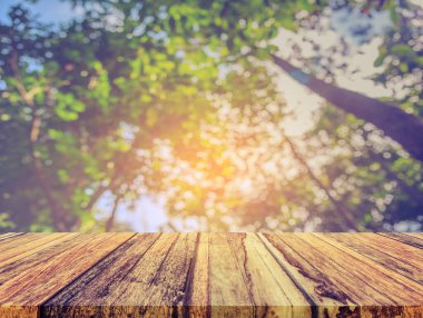 Arkaplan kullanımı için ahşap tablo ve yeşil ağaç bokeh 'in soyut bulanık resmi .