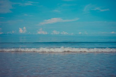 Arka planda mavi gökyüzü olan deniz kıyısındaki dalgaların görüntüsü.