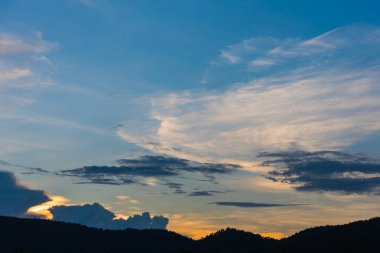 Arkaplanda dağ ve günbatımı görüntüsü.