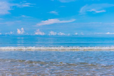 Arka planda mavi gökyüzü olan deniz kıyısındaki dalgaların görüntüsü.