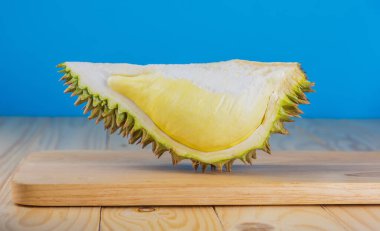 Ahşap masa üzerinde sarı posası olan olgun durian resmi.