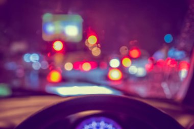 Arka plan kullanımı için camlara yağmur damlası konmuş ve gece vakti araba kullanan insanların klasik ton bulanık görüntüsü. (içeriden fotoğraf çek)