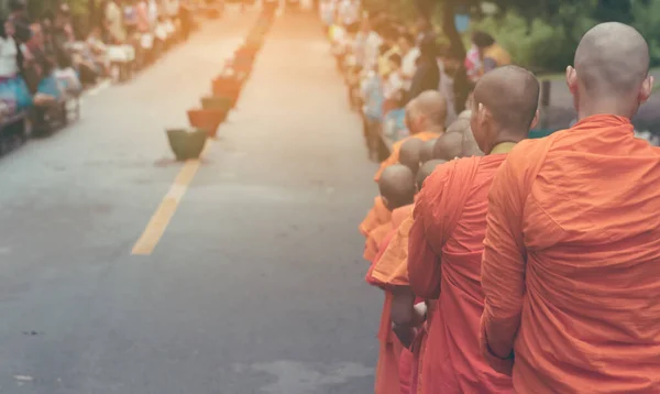 朝通りを歩く僧侶のヴィンテージトーンのイメージで食べ物を提供するのを待っている人々と — ストック写真