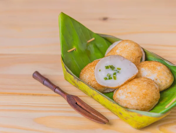 タイ風甘酸っぱい焼きココナッツライス木のテーブルの上にバナナの葉のプレートでホットケーキデザート — ストック写真