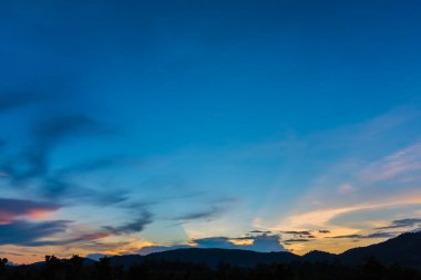 Arkaplanda dağ ve günbatımı görüntüsü.