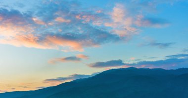 Tropikal yeşil dağ ormanları ve bulutlu gökyüzü günbatımı zamanı.