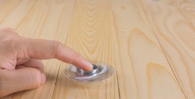 Tahta masanın üzerinde dönen oyuncakla (kıpırdanma) el resmi.