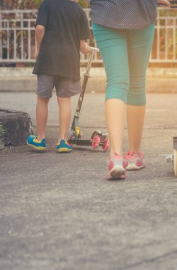 Sokakta scooter oynayan Asyalı kız ve erkek çocuğu