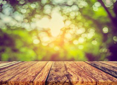 Arkaplan kullanımı için ahşap tablo ve yeşil ağaç bokeh 'in soyut bulanık resmi .