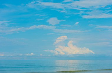 Denizde kayık resmi ve bulutlu mavi gökyüzü..