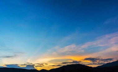 Arkaplanda dağ ve günbatımı görüntüsü.