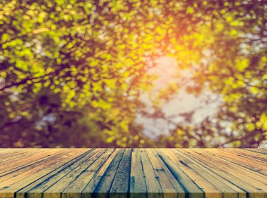 Arkaplan kullanımı için ahşap tablo ve yeşil ağaç bokeh 'in soyut bulanık resmi .