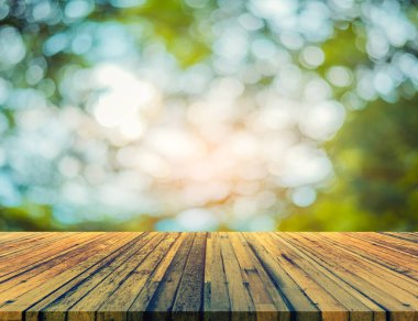 Arkaplan kullanımı için ahşap tablo ve yeşil ağaç bokeh 'in soyut bulanık resmi .
