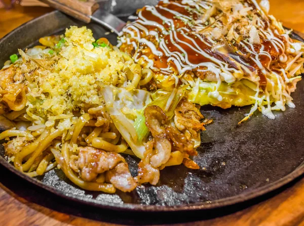 Närbild matlagning Okonomiyaki eller japan pizza med varmt strykjärn stekpanna — Stockfoto