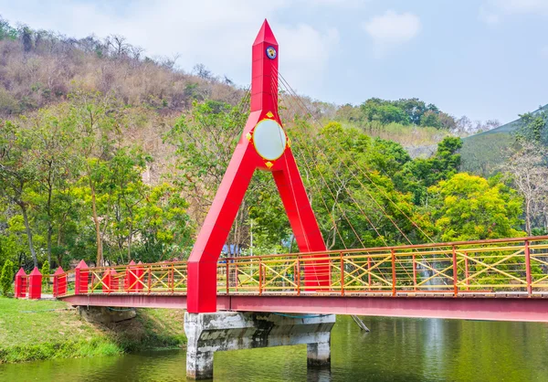 Imagen de Puente pintado en rojo que conduce a un bosque verde —  Fotos de Stock