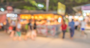 Şenlik ışıklarıyla süslenmiş caddedeki bulanık arka plan gece pazarının görüntüsü.