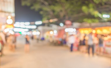 Şenlik ışıklarıyla süslenmiş caddedeki bulanık arka plan gece pazarının görüntüsü.