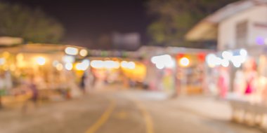 Şenlik ışıklarıyla süslenmiş caddedeki bulanık arka plan gece pazarının görüntüsü.