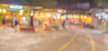 Şenlik ışıklarıyla süslenmiş caddedeki bulanık arka plan gece pazarının görüntüsü.