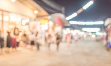 Şenlik ışıklarıyla süslenmiş caddedeki bulanık arka plan gece pazarının görüntüsü.