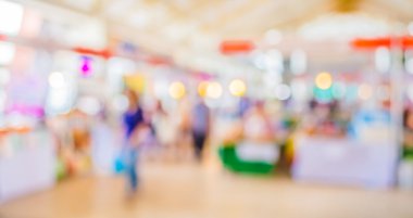 Güneşli bir günde gündüz pazarında yürüyen insanların bulanık görüntüsü. 