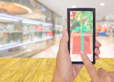 bir modern dokunmatik ekran telefon ve alışveriş merkezi ve insanların arka plan, odak ve sığ derinliği erkek elini tutuyor .