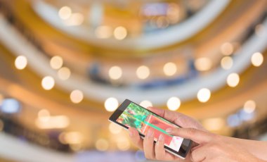 bir modern dokunmatik ekran telefon ve bulanık görüntü alışveriş merkezinde yürüyen insanların bokeh ile arka plan bulanıklık erkek elini tutuyor