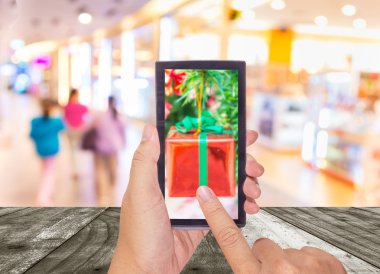 Erkek el bir modern dokunmatik ekran telefon tutarak ve alışveriş merkezi ve insanlar görüntü bulanık .