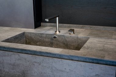 Koyu bej mermer leğen ve parlak metal karıştırıcı.