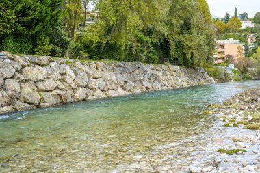 Su, köyün yakınındaki bir nehrin kayalıklarında hızlı akar. Önünde orman ve nehir var. Güzel manzara.