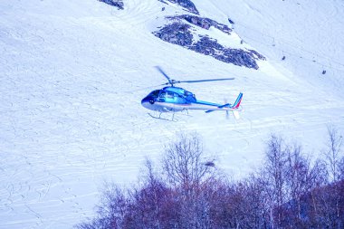 Helikopter L 'Alpes D' Huez, Fransa 'daki kar dağına indi. Helikopter servisi manzaralı uçuşlar, buzulların inişi ve acil kurtarma hizmetleri sunuyor. Mavi dağ