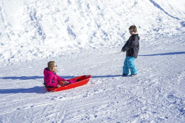 Kardeşinin çocukları kızak kızağıyla kayıyor. Küçük kız ve oğlan kızak sürüşünün keyfini çıkarıyorlar. Çocuk kayağı. Çocuklar karda dışarıda oynarlar. Çocuklar kızak.