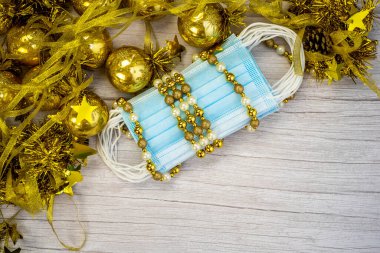 Mavi tıbbi korona virüslü kompozisyon, maske ve ahşap arka planda altın toplarla süslenmiş kış dekorasyonuyla karşılaşıyor. Covid-19 salgınında mutlu Noeller. Yüksek kalite fotoğraf