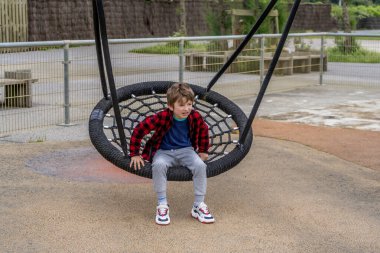 Oyun bahçesinde sallanan örümcek ağlarıyla oynayan mutlu çocuk salıncakta sallanırken gülen bebek dışarıda çocuk aktiviteleri yapan çocuk.. 