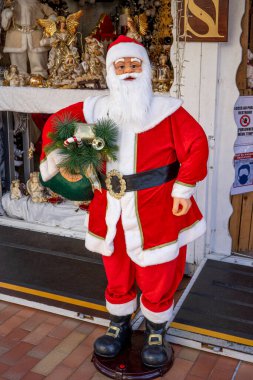 Monte-Carlo, Monaco 29.11.2020 Komik kırmızı Noel Baba ve güzel Noel oyuncakları vitrinde, bir sürü süs ve hediye. Noel 'in şenlikli kış ticareti, alışveriş. 