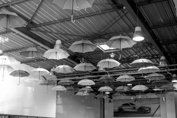 Various umbrellas hung under the ceiling. Black and white photo — Fotografia de Stock